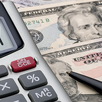 U.S. paper bills, a calculator, and a pen