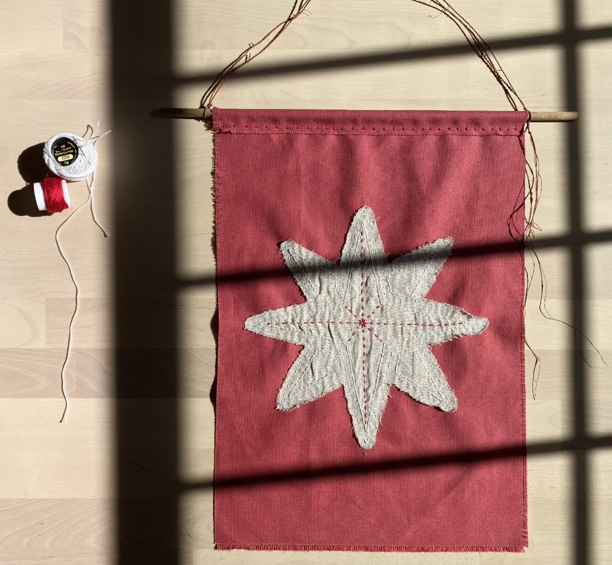 A red flag with a white star on top and yarn on the side. 