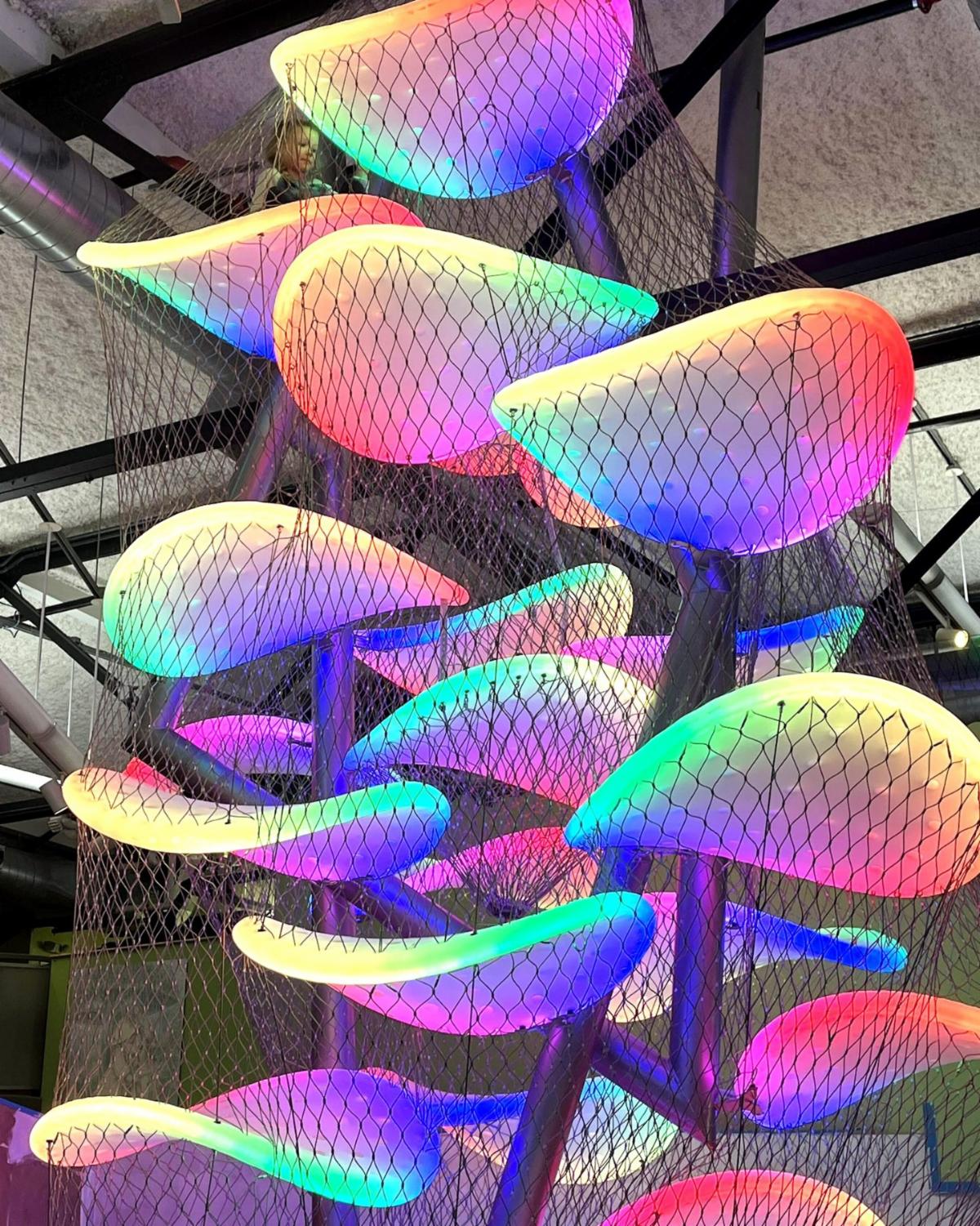 A child sits at the top of a colored climbing structure