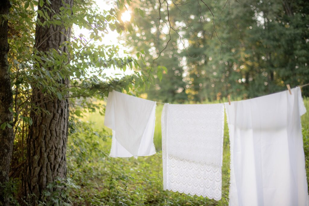 A clothesline between two trees with clothes drying on it; photo by Carly Mackler on Unsplash