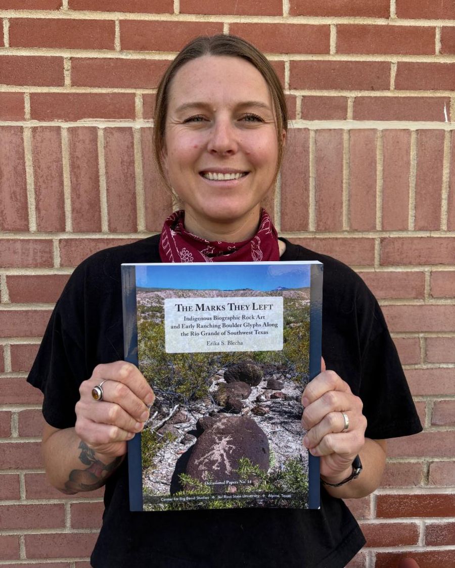 Erika Blecha holding the book The Marks They Left. 