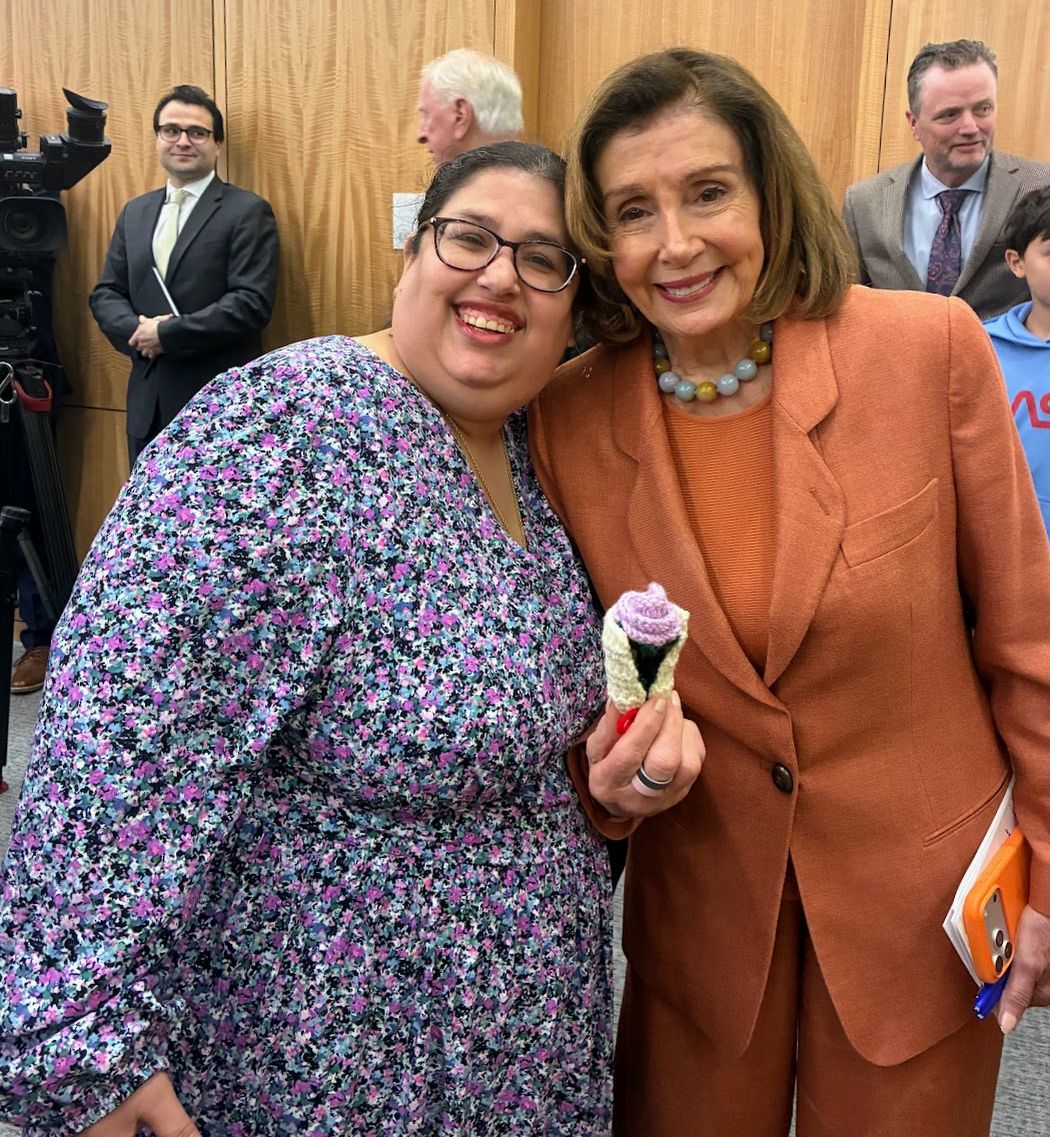 Gaby stood beside Nancy Pelosi, who was holding a crocheted flower that Gaby had made for her. 