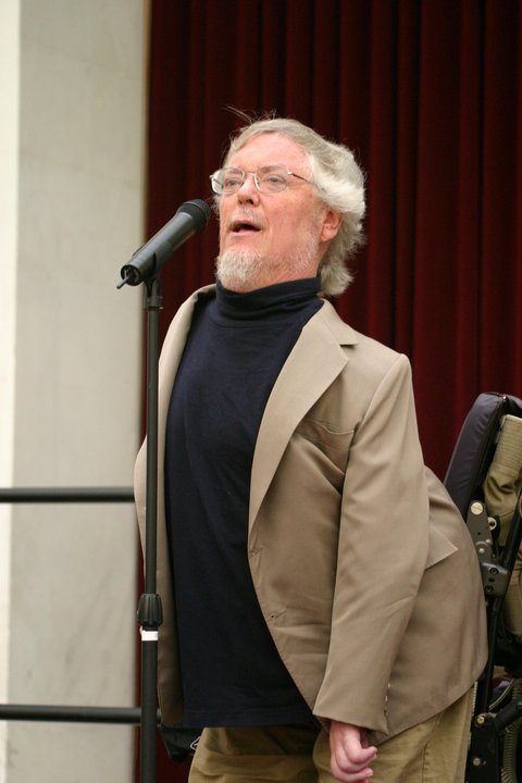 Paul Longmore speaking into a microphone at an ADA celebration.