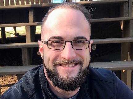 White male, glasses, beard and black tshirt 