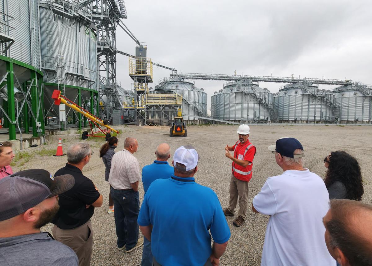 A group of people in front of giant grain bins.