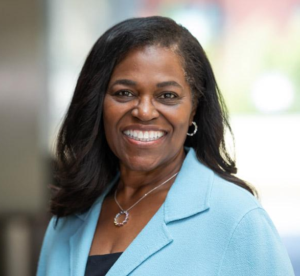 Headshot photo of Renee Navarro wearing light blue blazer and necklace, smiling. 