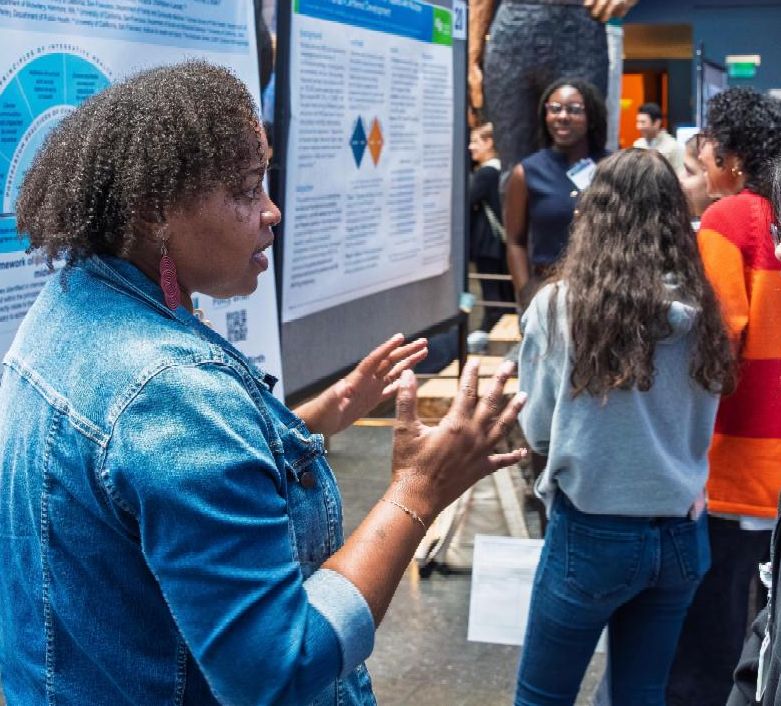 Photo of person explaining poster with poster in background