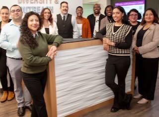 Photo of resource centers staff and colleagues standing around reception desk of resource centers. All are smiling and the feeling is welcoming. 