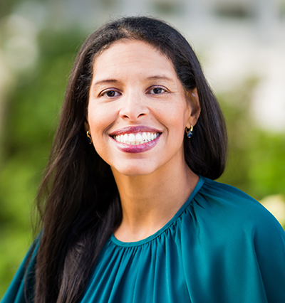 Headshot photo of Michelle Guy outside wearing teal shirt and smiling. 