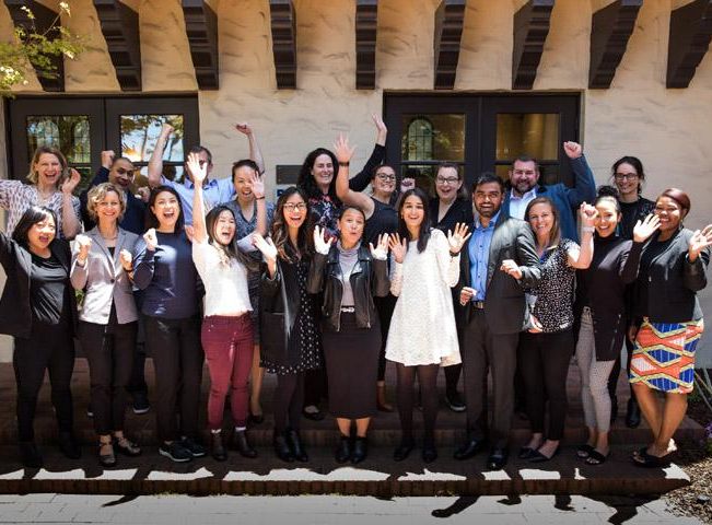 Photo of program participants smiling and holding up hands in celebration outside.