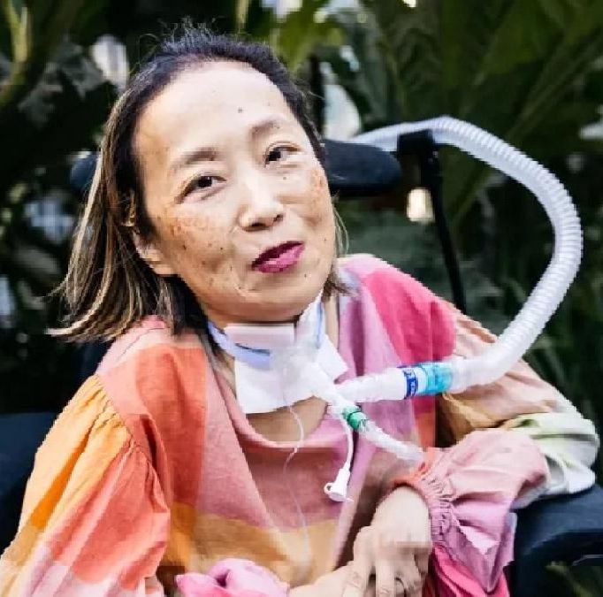 Photo of Alice Wong smiling with bright shirt on outside.