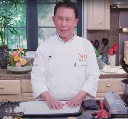 Shot from video of Martin Yan in white chef's coat in a kitchen while speaking to camera.