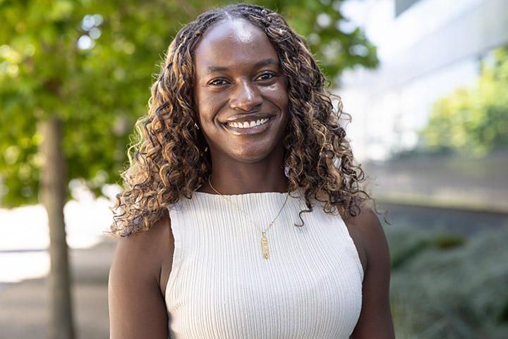 Photo of Chiara Blake wearing cream shirt and necklace smiling outside. 