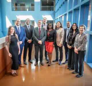 Group photo taken in a well-lit indoor space of UCSF Chancellor, Sam Hawgood, with Vice Chancellor Renee Navarro, and the 2025 award recipients. 