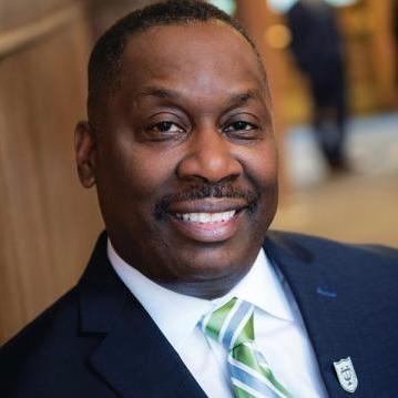 Thomas LaVeist, PhD, smiles in headshot-style photo wearing dark suit and green tie