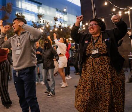 Photo of peple dancing at Bailamos with lights in background.
