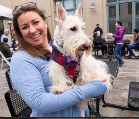 A woman holds a white scotty dog.