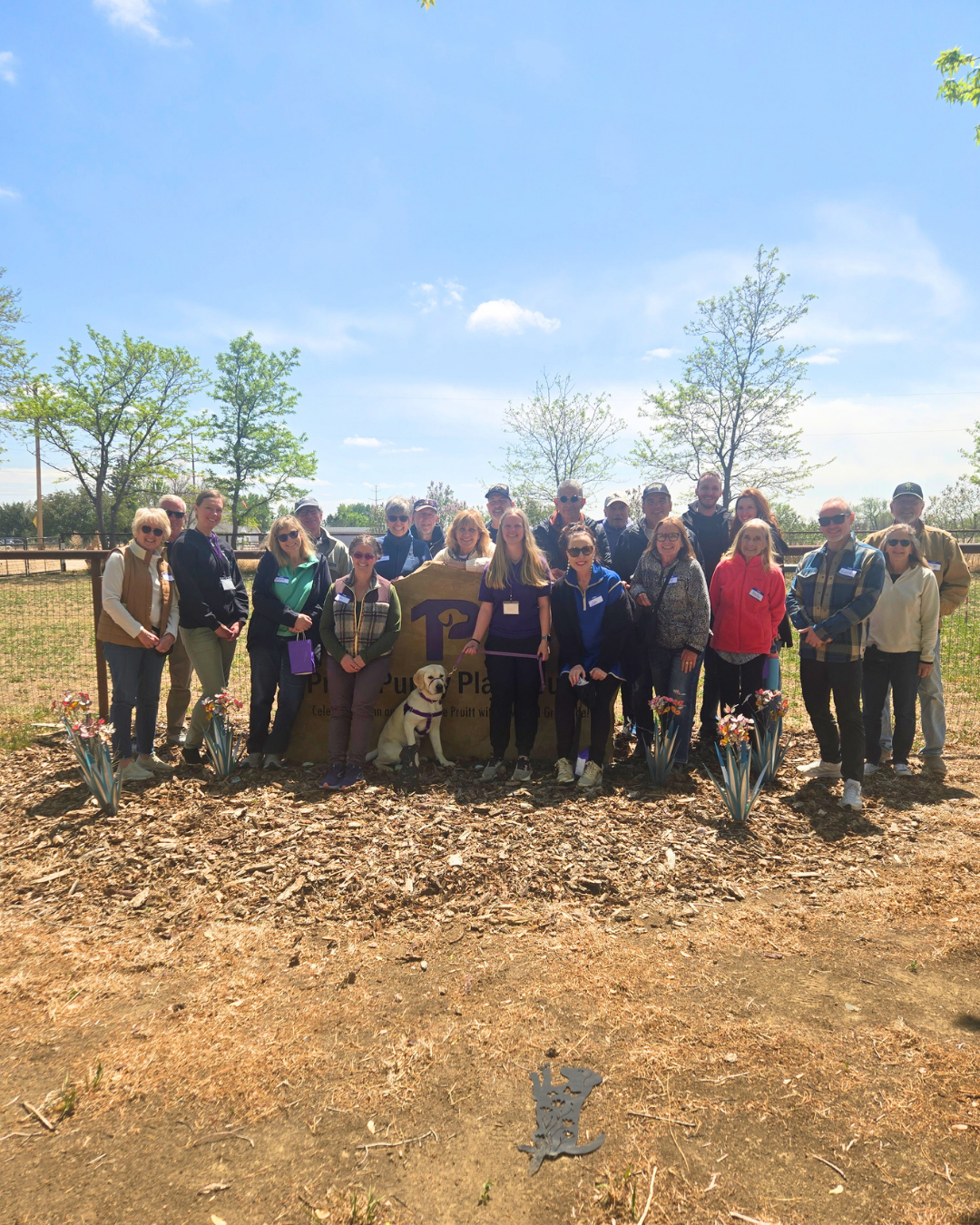 Twenty volunteers gather around a Paragon sign outside for a photo. 