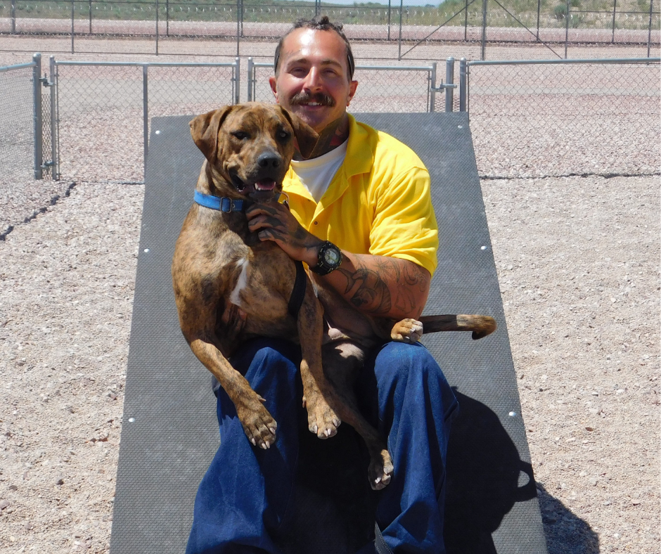 Hunter, holds a brown bully mix dog beaming at the camera. 