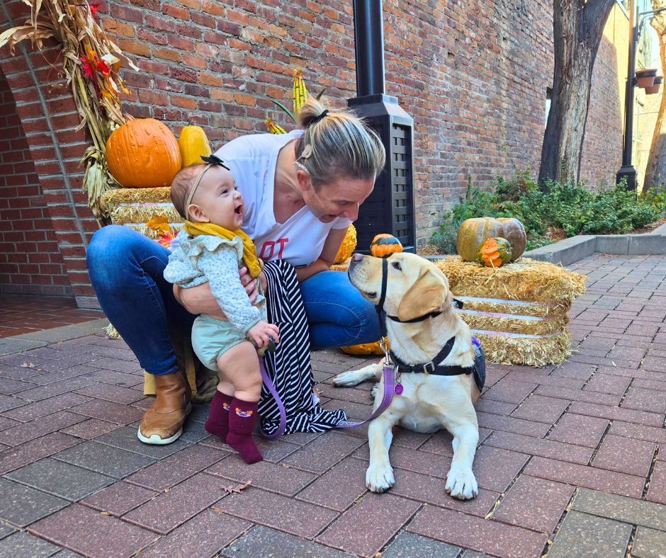 Outside next to fall decorations Dancer, Tia, and her six month old baby girl smile together for a photo.