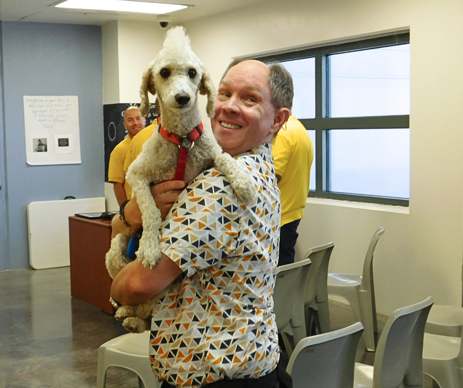 Harvey holds a white doodle named Astro. He is beaming at him. 
