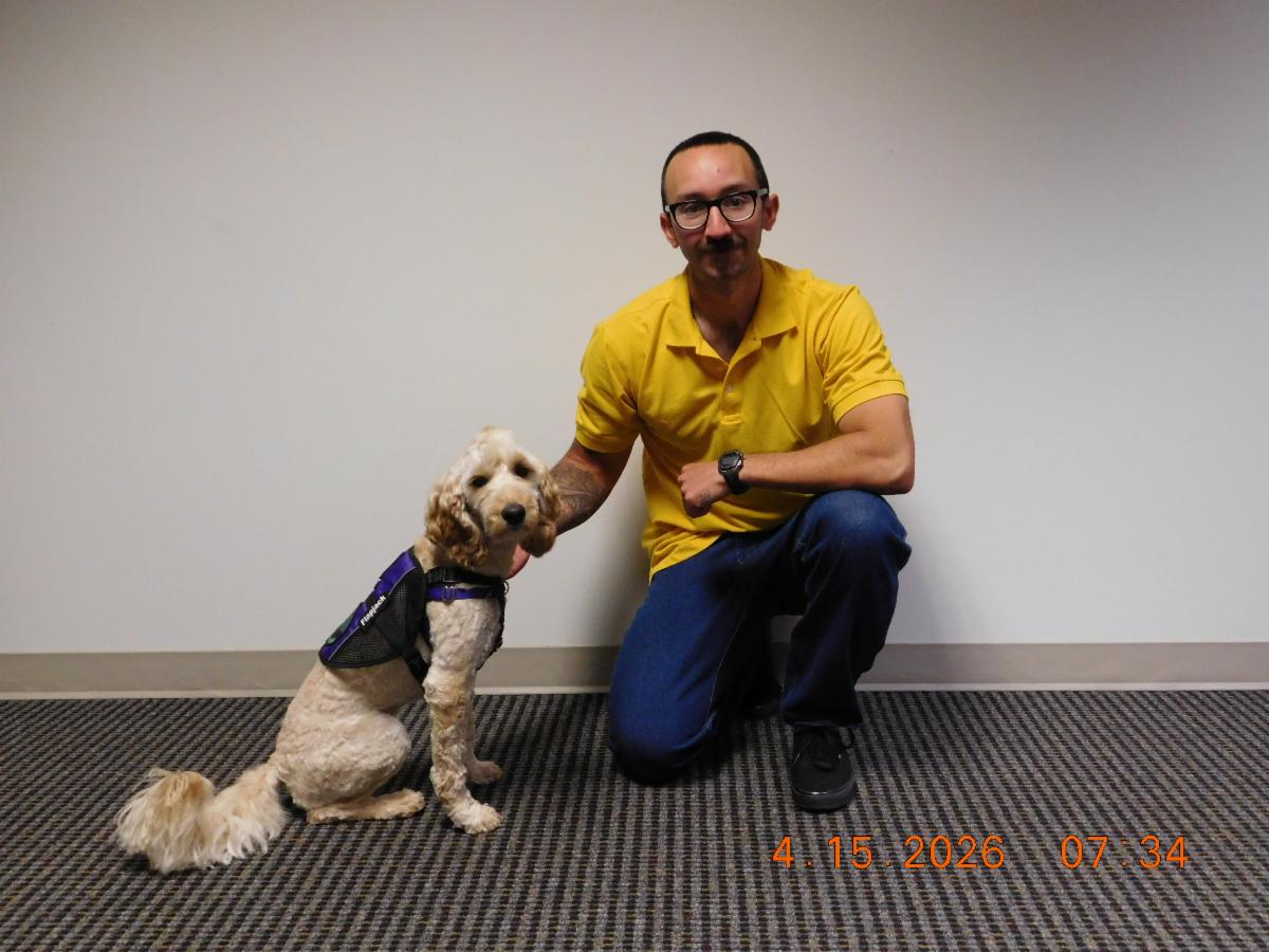 A cobber dog named FlapJack poses next to his smiling inmate handler. 