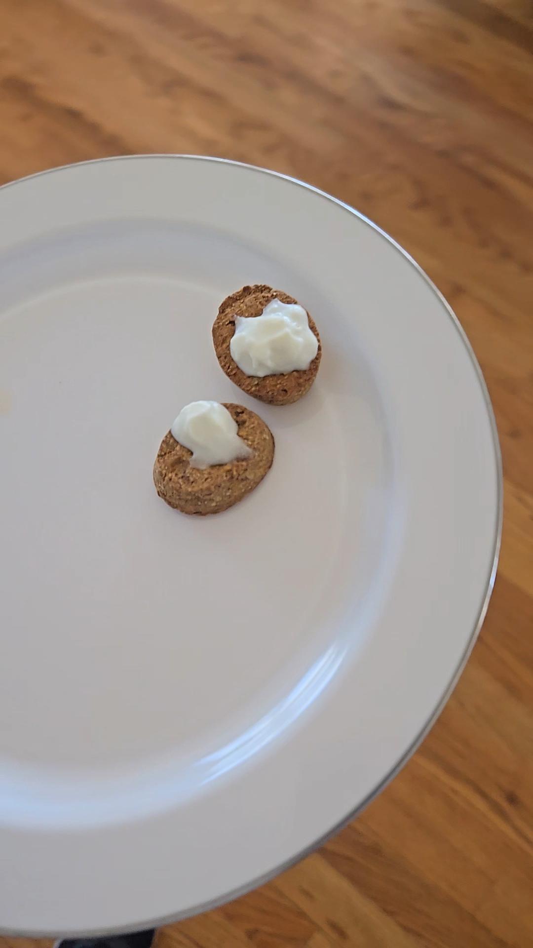 On a white plate there are two pies with whip cream. 