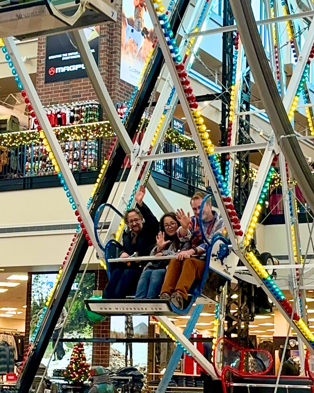 Two Paragon Staff and Client Matt wave from a Farris wheel. 