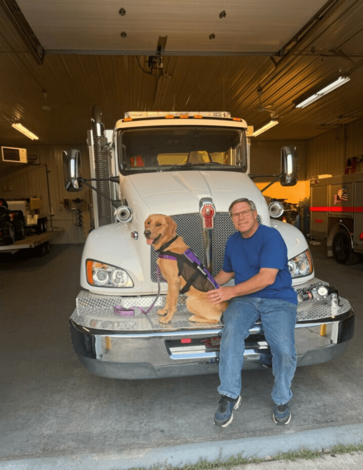 •	Ender a golden Lab sits on the bumper of a white truck beside Kathys husband.
