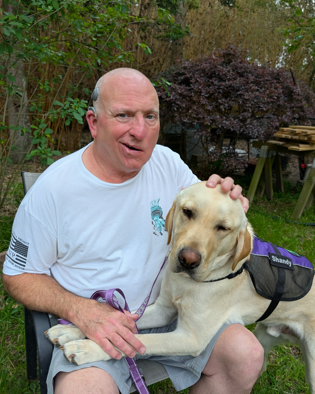 Client Perry smiles next to her hearing dog a yellow lab named Shandy.