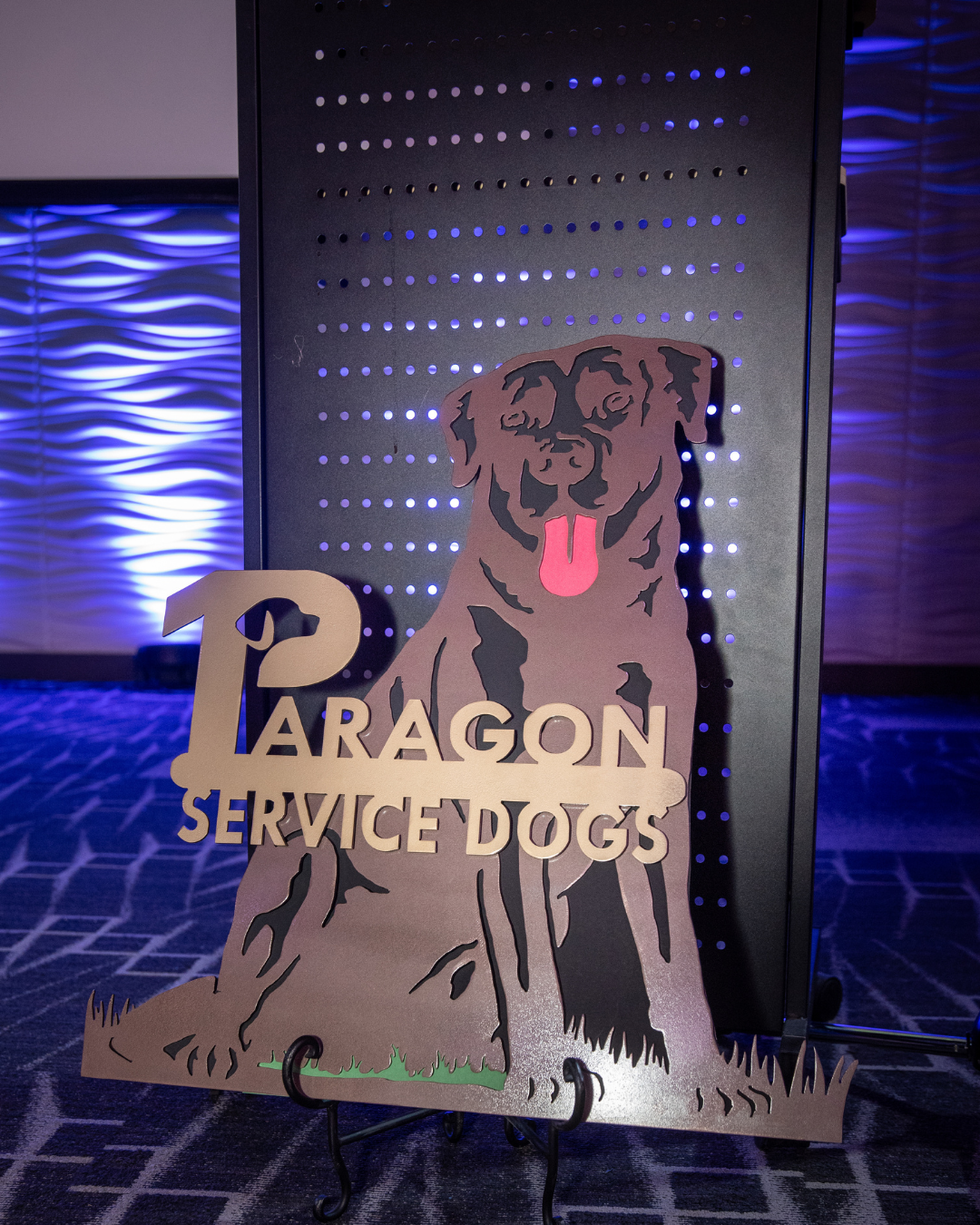A metal sign of a chocolate lab says Paragon Service Dogs.