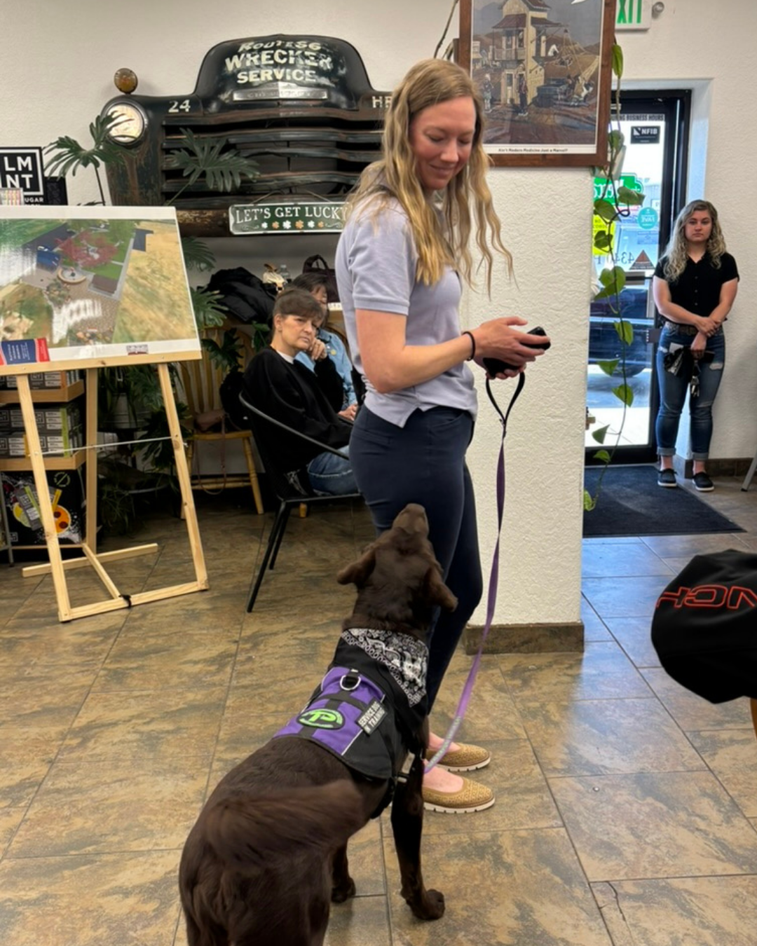 Trainer Leah smile at Epic, a chocolate lab as he looks up at her. 