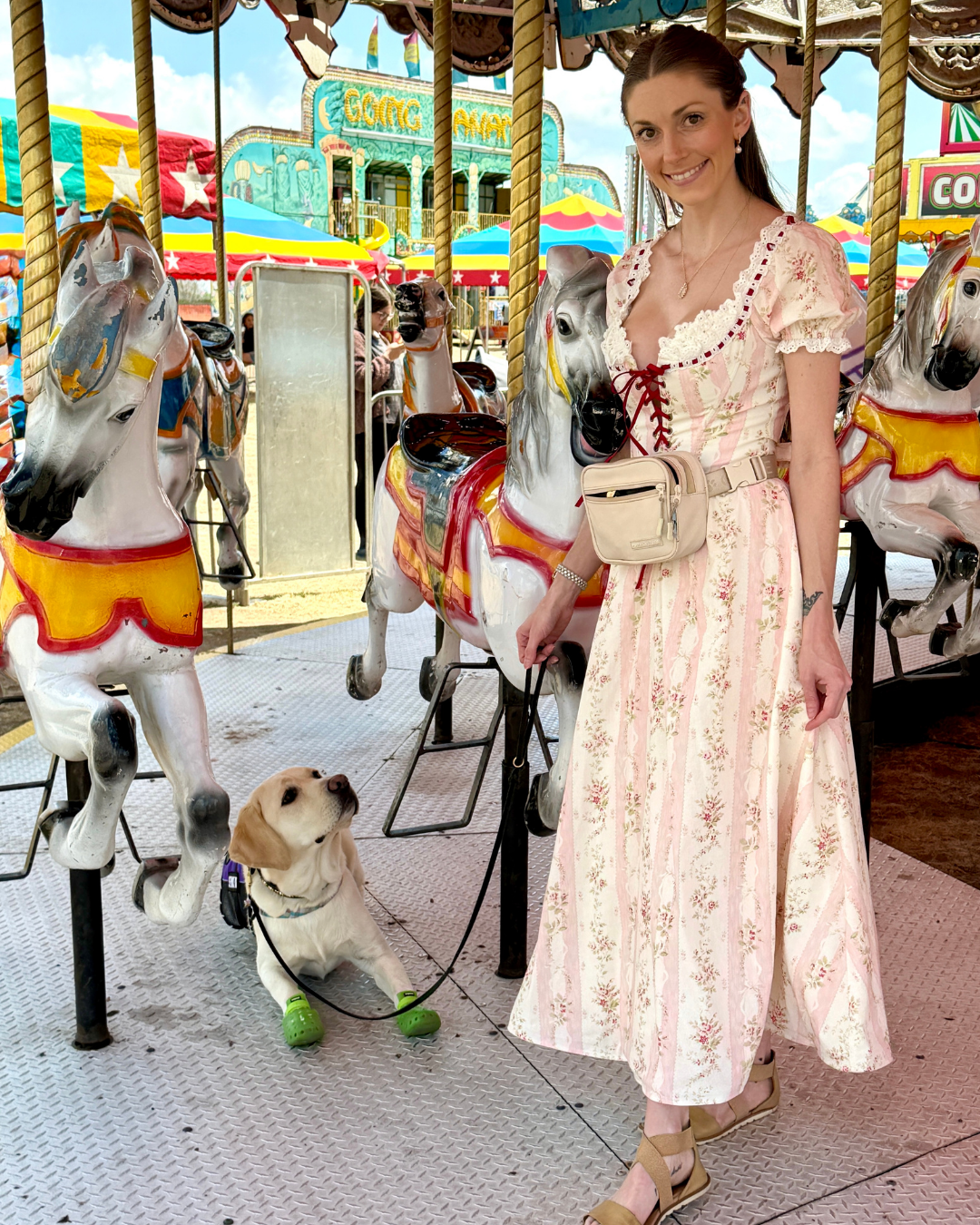Courtney and her service dog Caro pose on a carousel. 