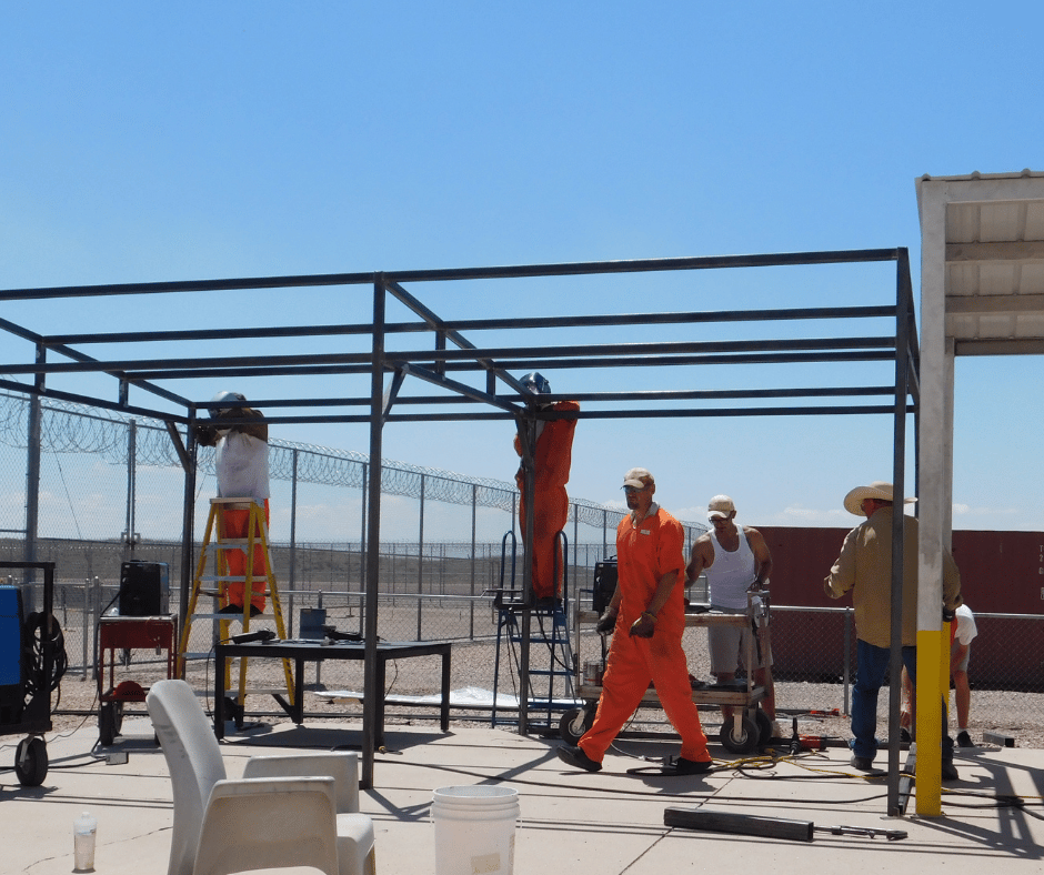 Four inmates hold up various pieces of a mental structure. It looks more complete with all four sides. 