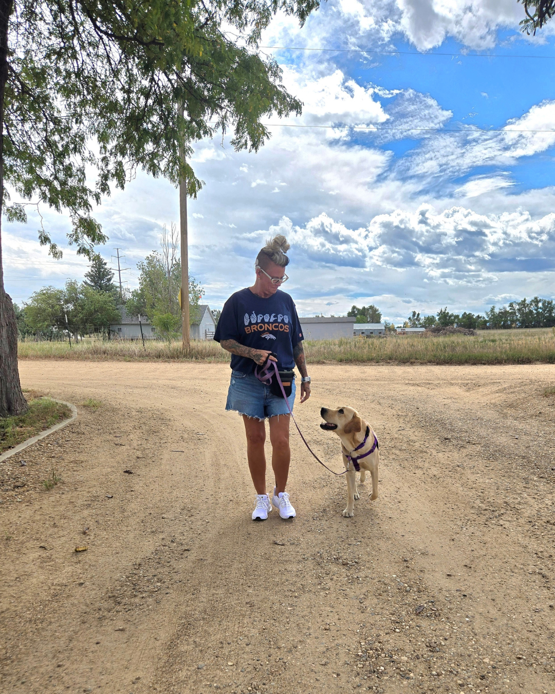 Melissa walks with Fortune outside down a dirt path. Both are looking at each other lovingly. 