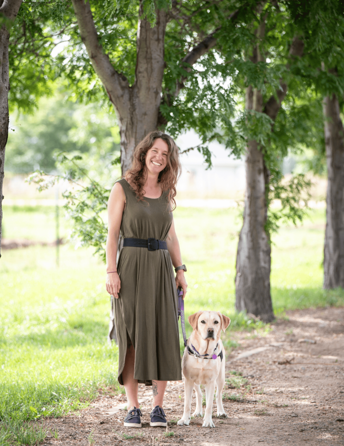 Client Christina smiles next to her hearing dog a yellow lab named Danny.