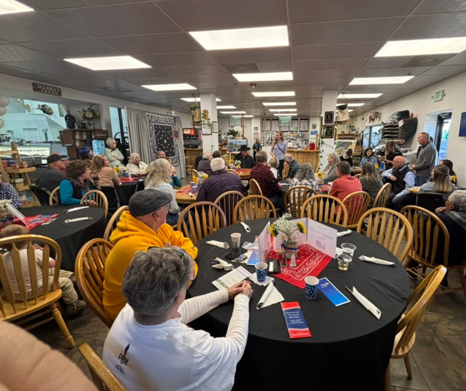 A room full of about 20 people sitting at tables. 