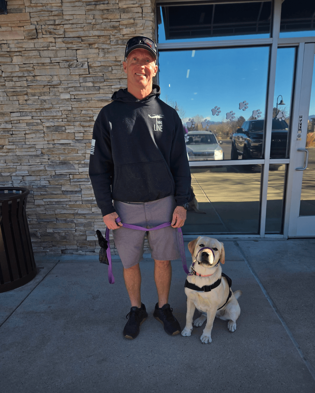 Yellow lab Fiona sits next to her smiling puppy raiser.
