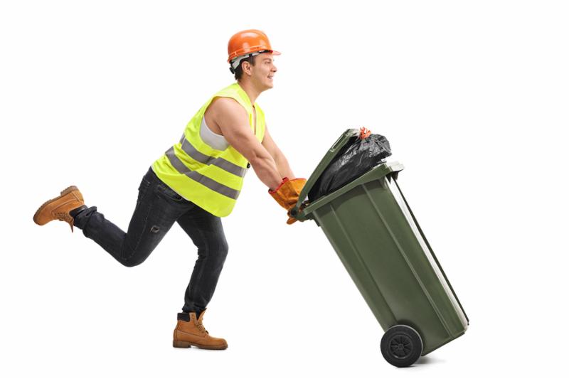 Excited young waste collector pushing a trash can and running isolated on white background