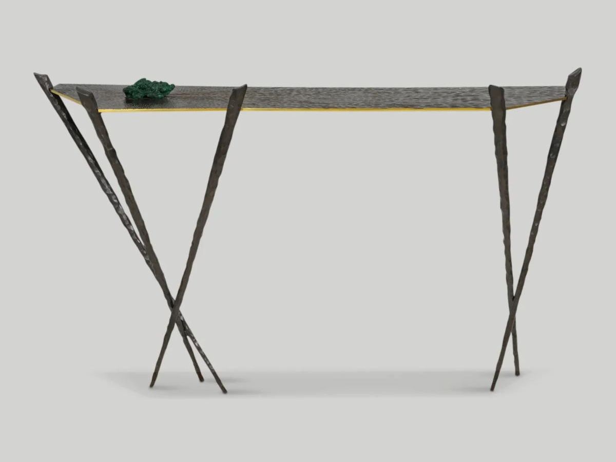 A textured black steel gold-trimmed console with six angled legs and a geometric tabletop. 