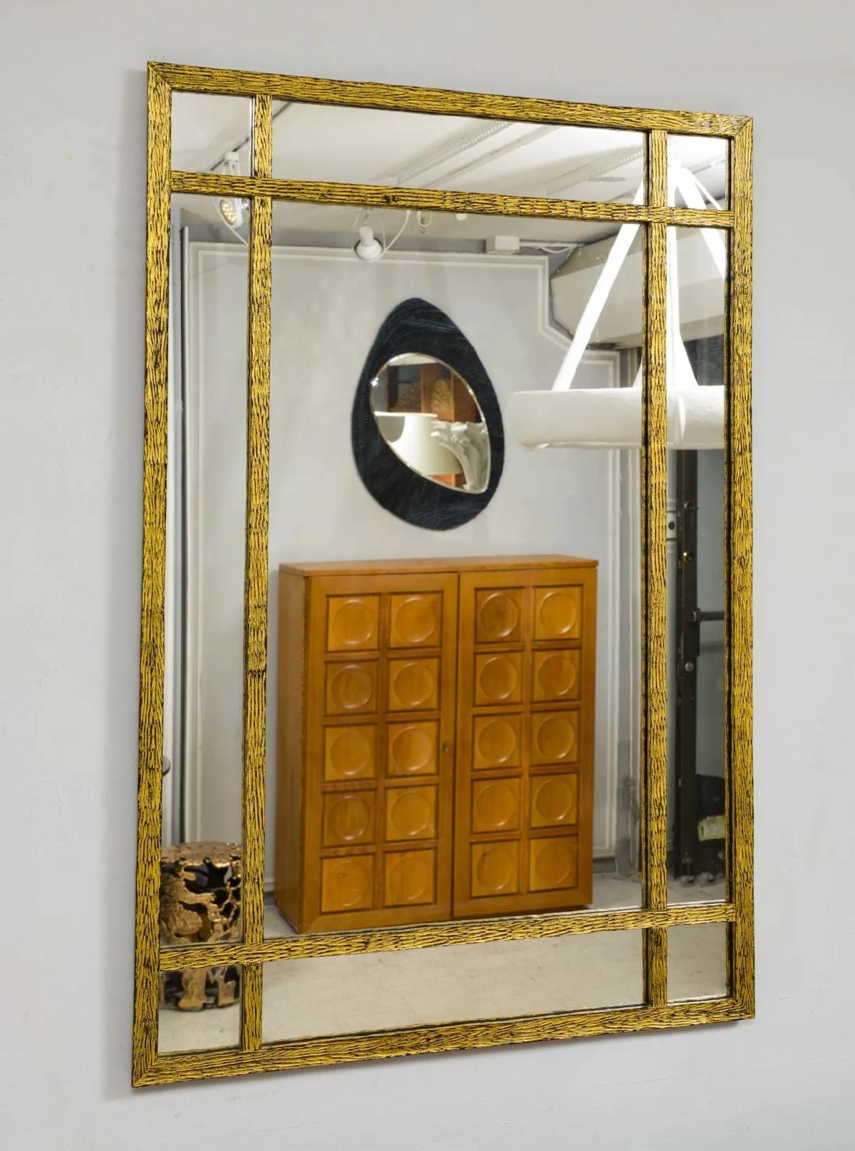 A wall mirror with gold rectangular border design.