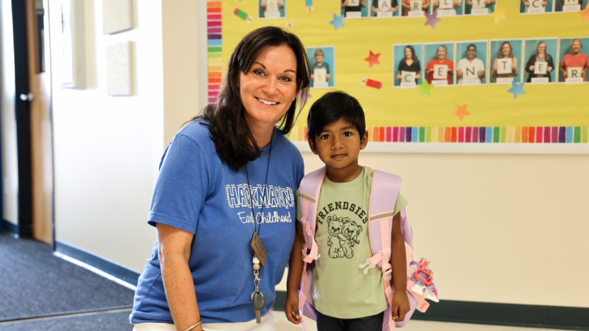 A Hackmann Early Childhood employee and student pose for a photo in the hallway. 