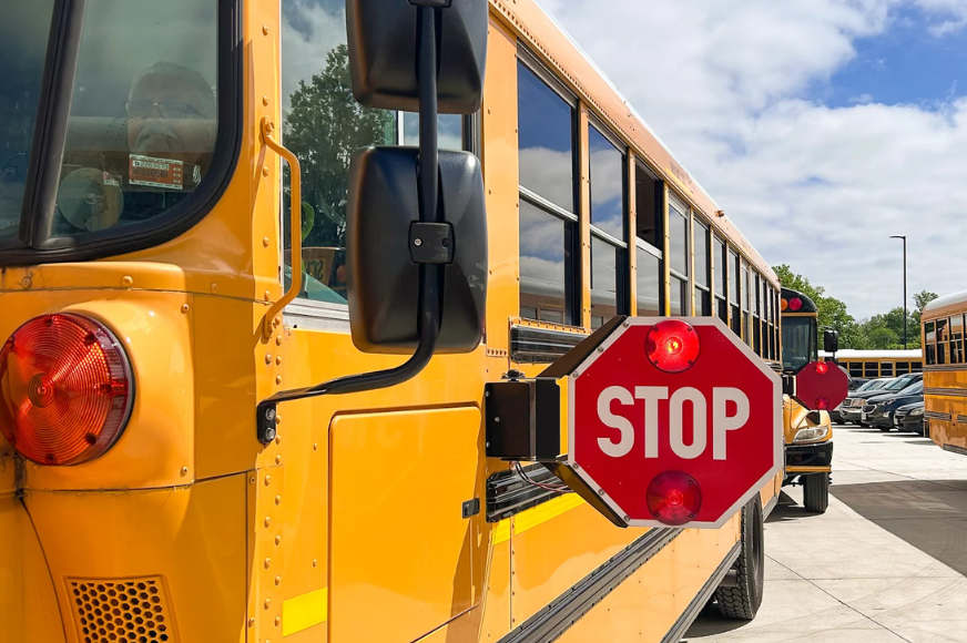 A yellow school bus with its stop sign extended