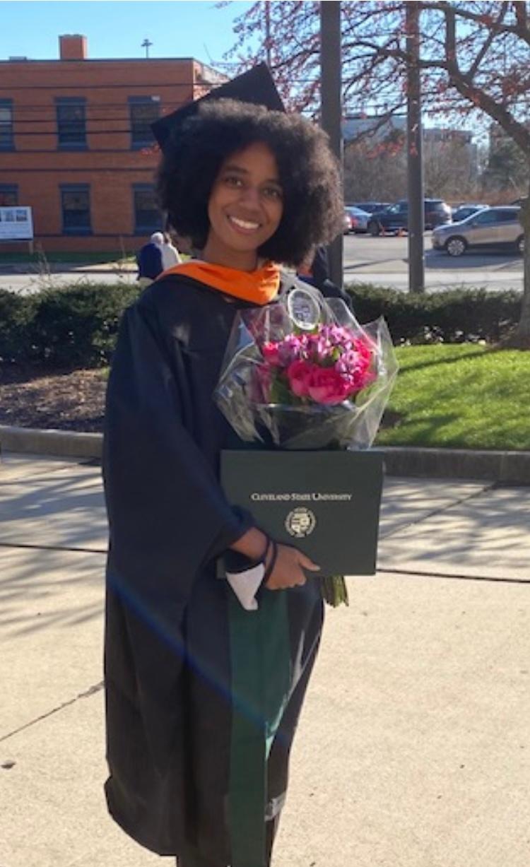 Bre Turner in cap and grown holding flowers and graduate certificate