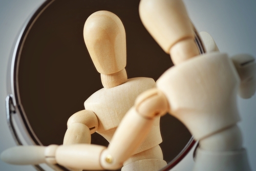 Wooden mannequin looking at himself in the mirror - Concept of interiority_ introspection and self-reflection