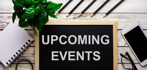 UPCOMING EVENTS is written in white on a black board next to a phone_ notepad_ glasses_ pencils and a green plant.