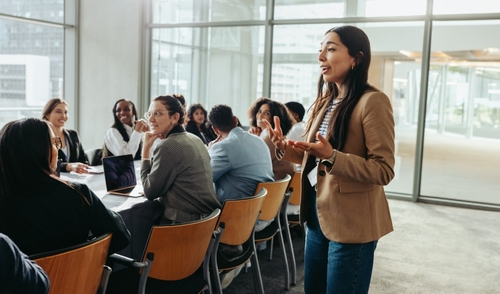 A confident female leader engages a diverse team in a professional workshop_ promoting teamwork and fresh ideas in a bright office environment.
