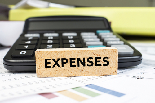the word expenses is written on a wooden cube. Calculator and business documents. Business and financial concept.