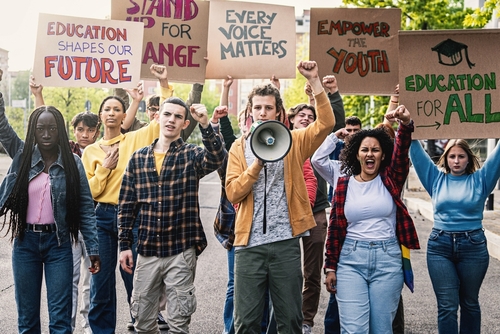 Multiracial Students Protesting for Education - Diverse group of young students marching_ raising clenched fists and holding signs advocating for change in education.