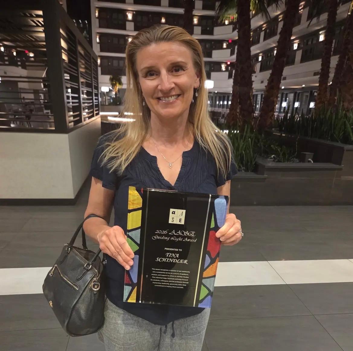 Tina Schindler holding 2026 AASE Guiding Light Award